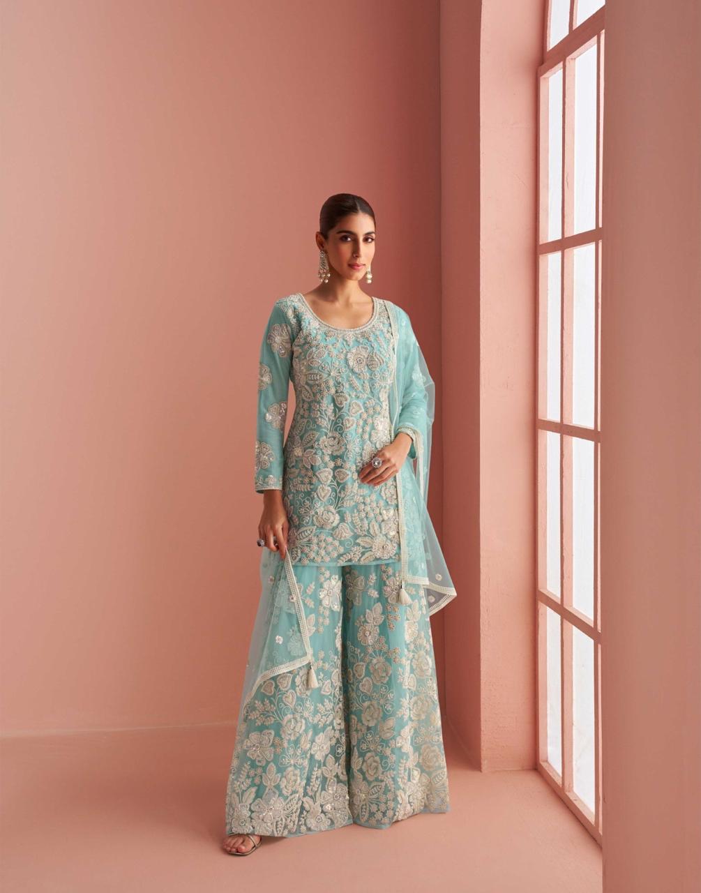 Model wearing a teal blue sharara standing in front of a rose gold background.