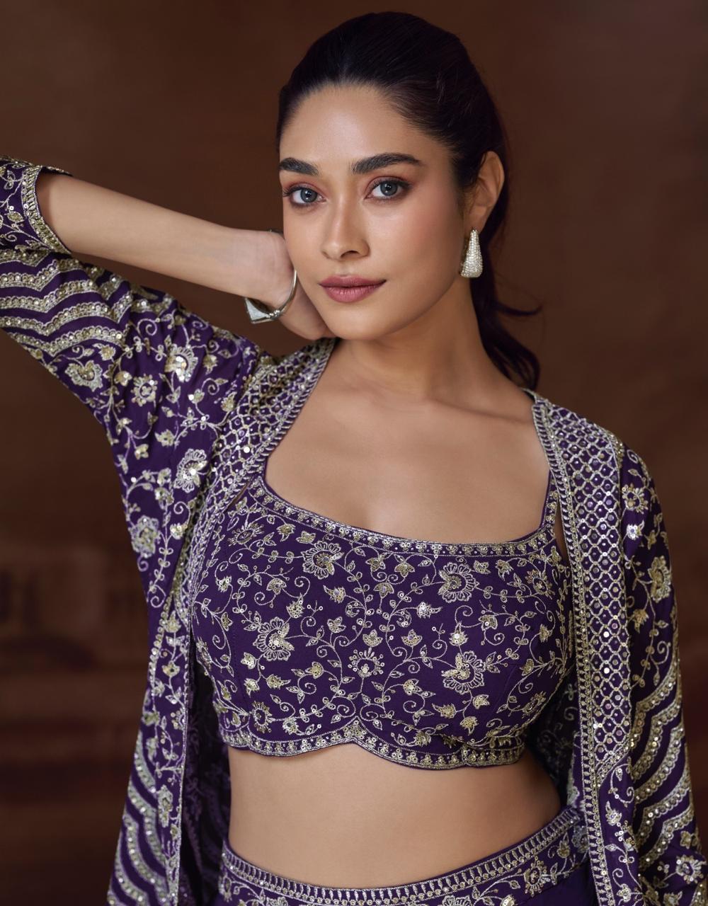 Woman wearing a traditional purple and white embroidered outfit against a brown background