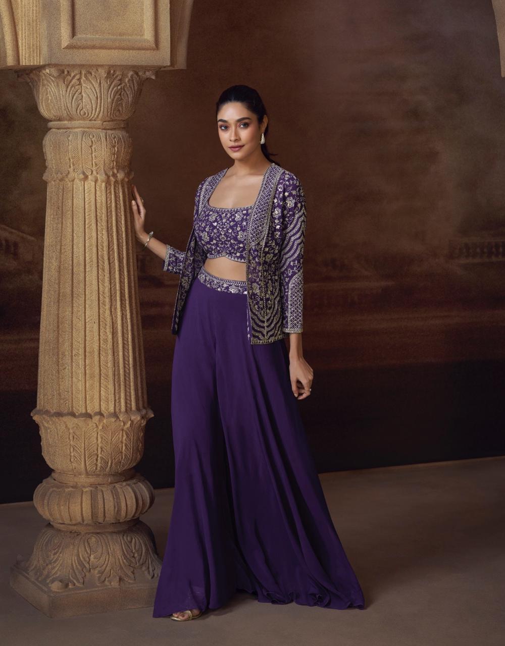 Woman in a purple traditional outfit standing next to a decorative column.