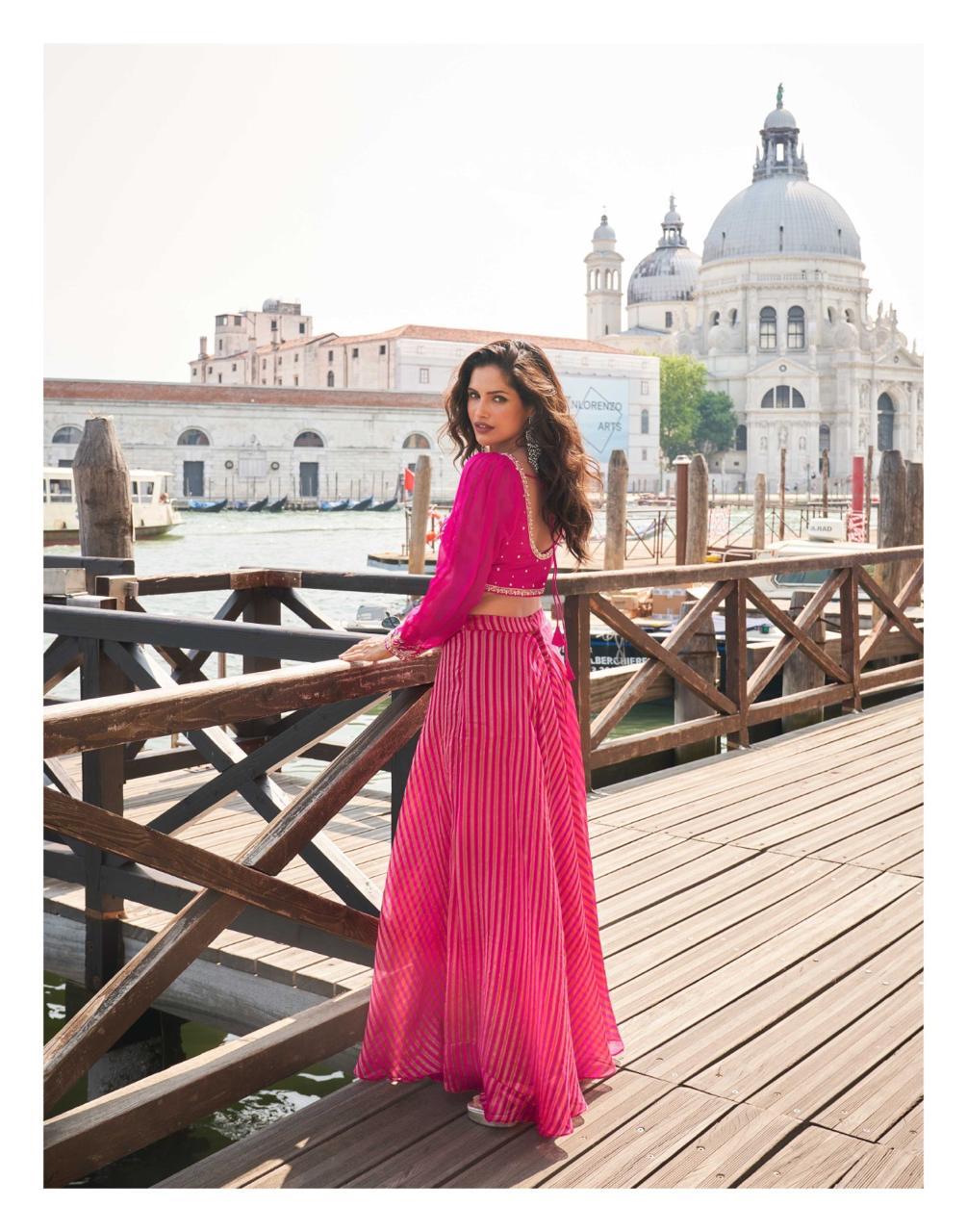 Woman in a pink outfit standing on a wooden bridge with a scenic background
