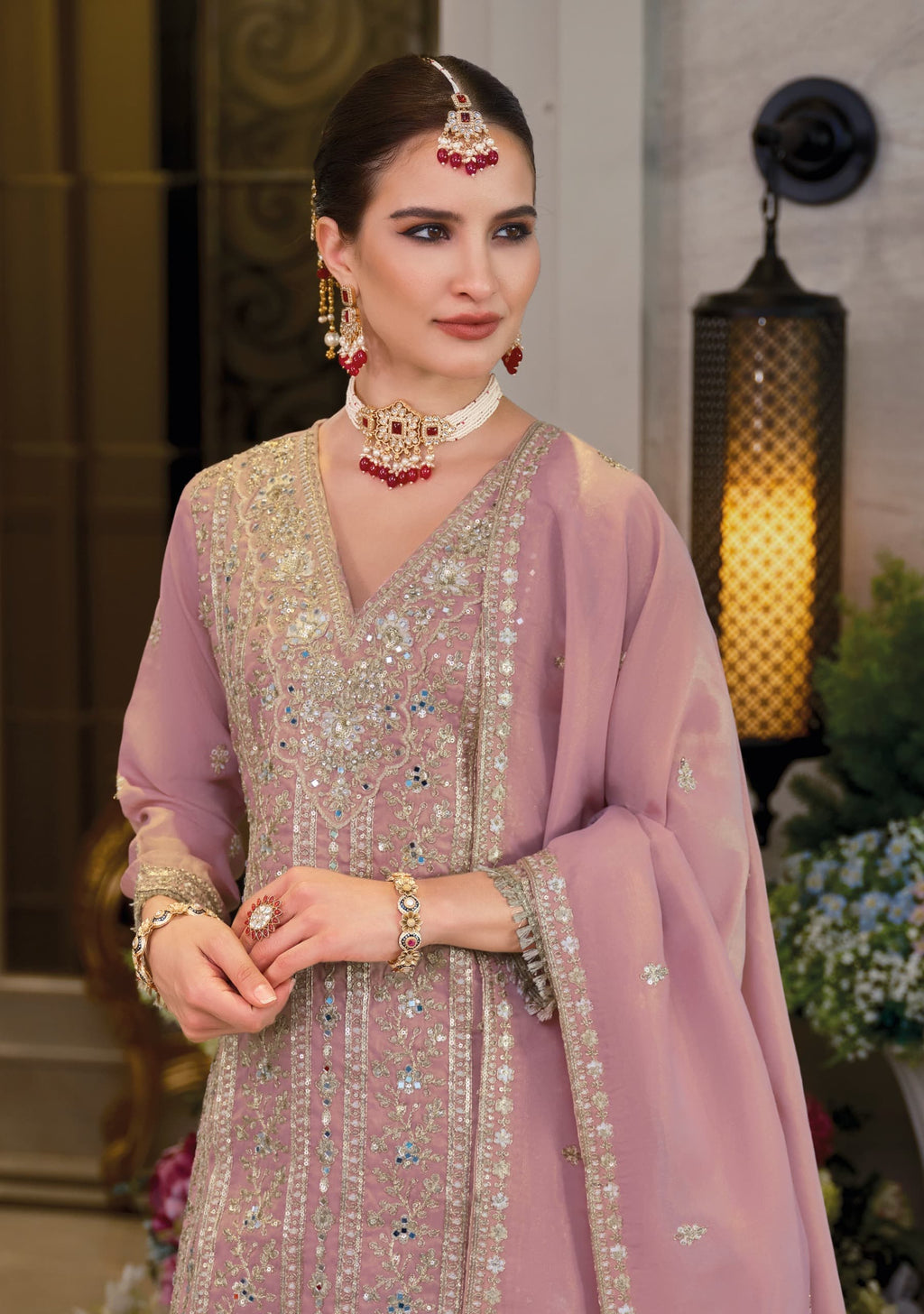 Woman in traditional pink and silver outfit with jewelry indoors