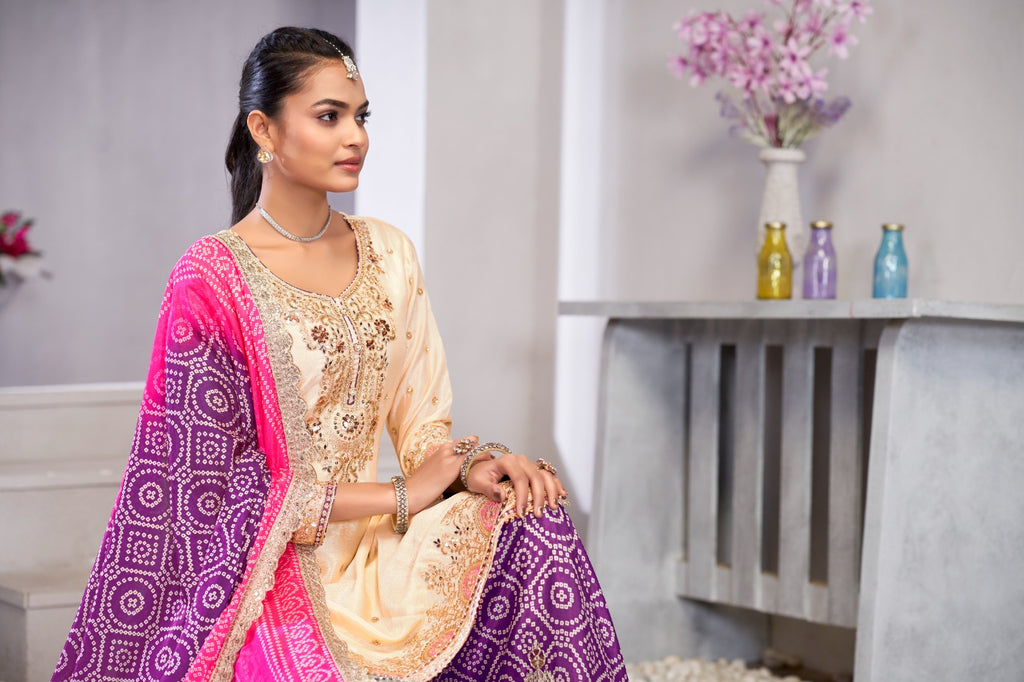Woman in traditional outfit with pink and purple dupatta in a room setting