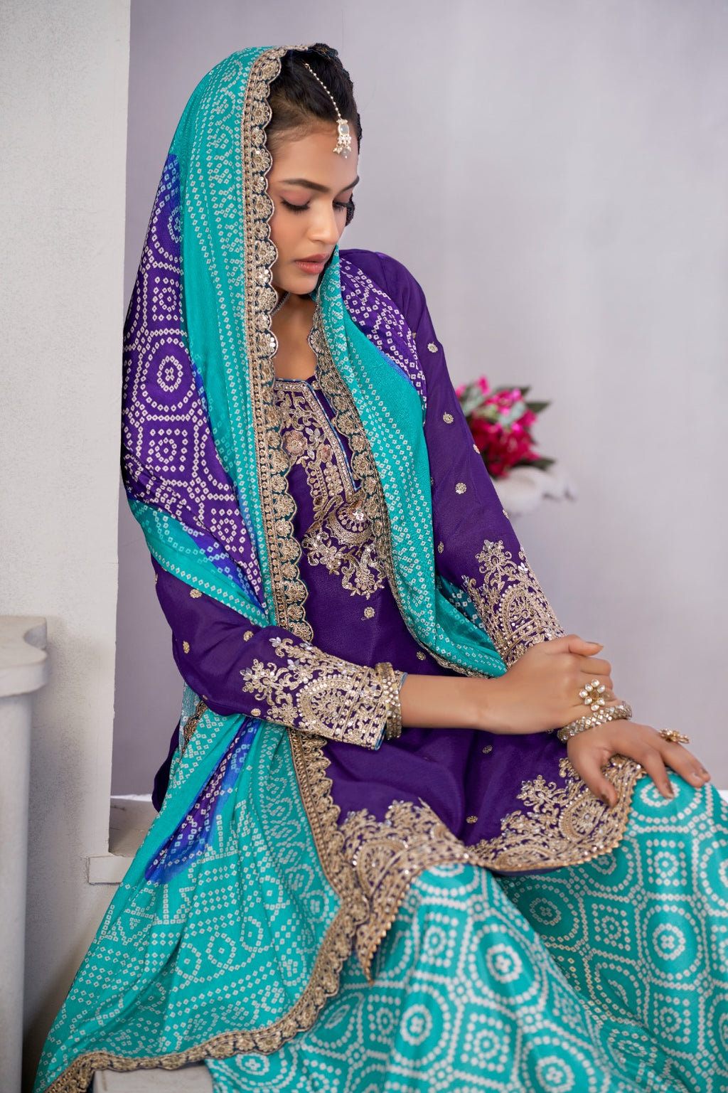 Woman in a traditional purple and teal outfit with intricate patterns.