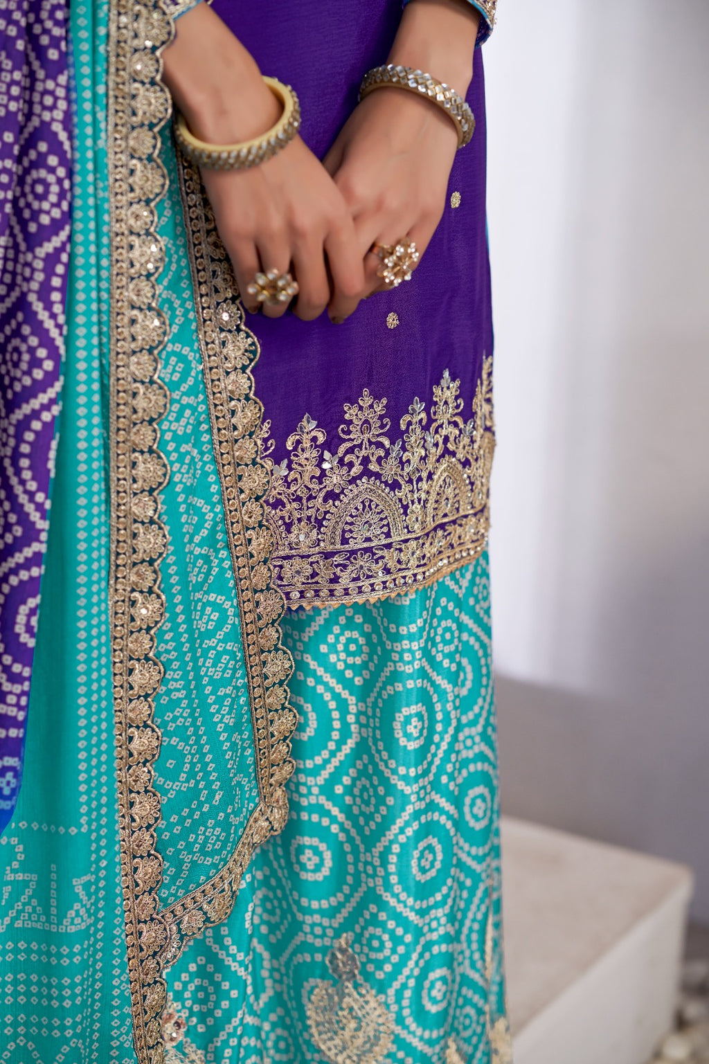 Close-up of a teal and purple embroidered traditional outfit with gold detailing.