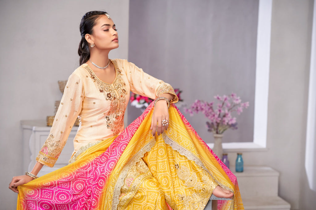 Woman in traditional outfit with yellow and pink dupatta in a room setting