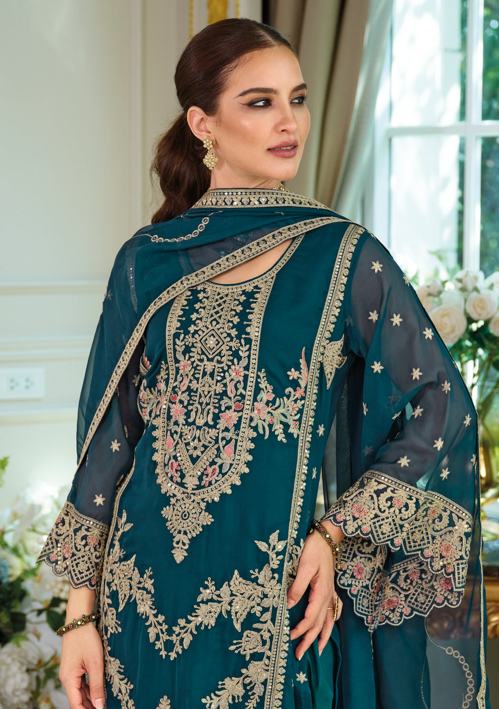 Woman wearing a teal blue salwar kameez suit, front.