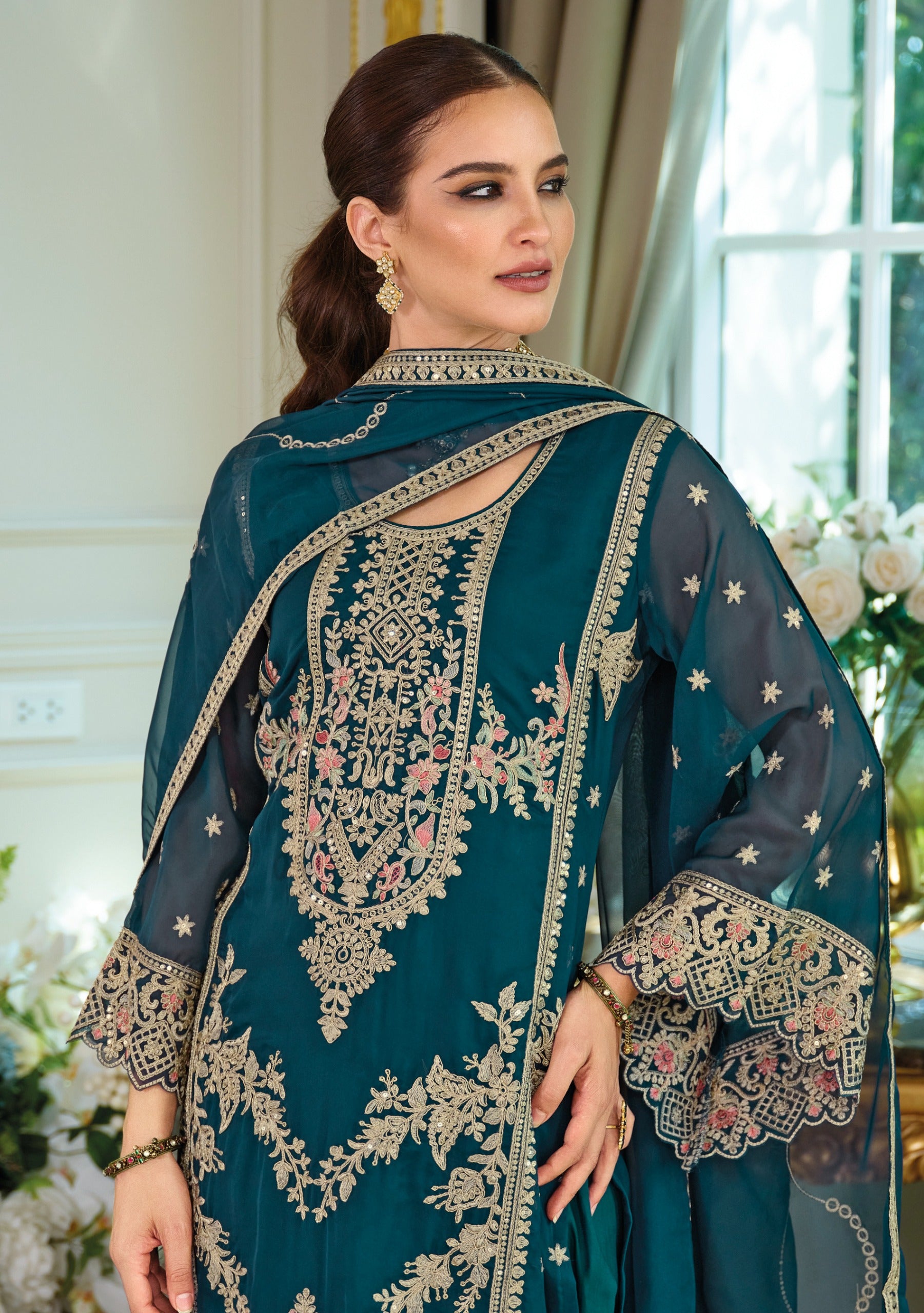 Woman wearing a teal blue salwar kameez suit, front.