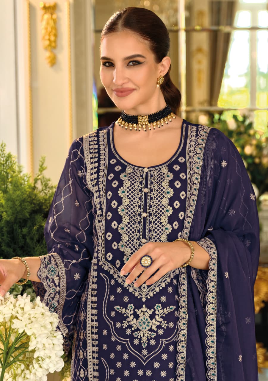 Woman wearing a traditional embroidered outfit with jewelry indoors.
