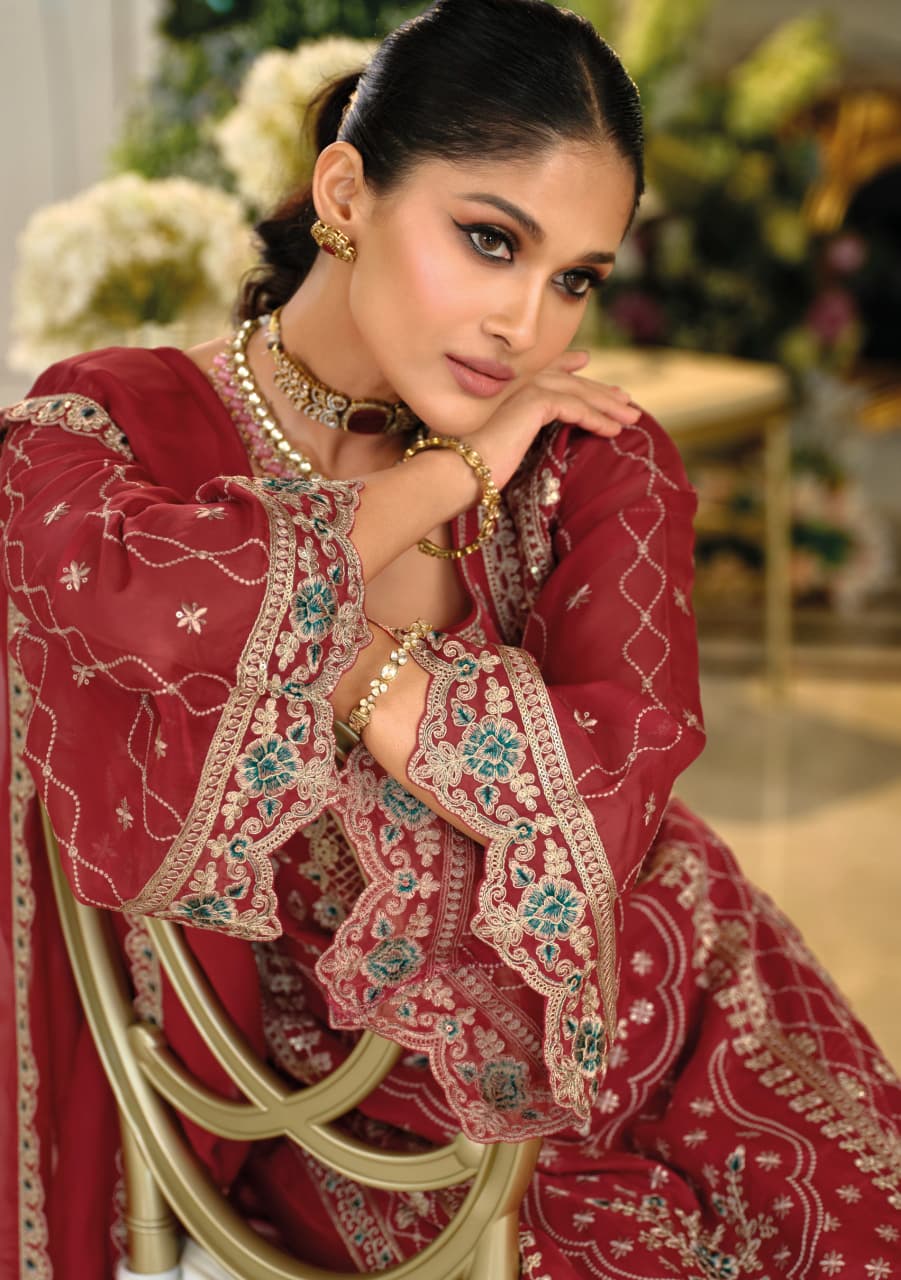 Woman in a red embroidered traditional outfit sitting on a chair with flowers in the background
