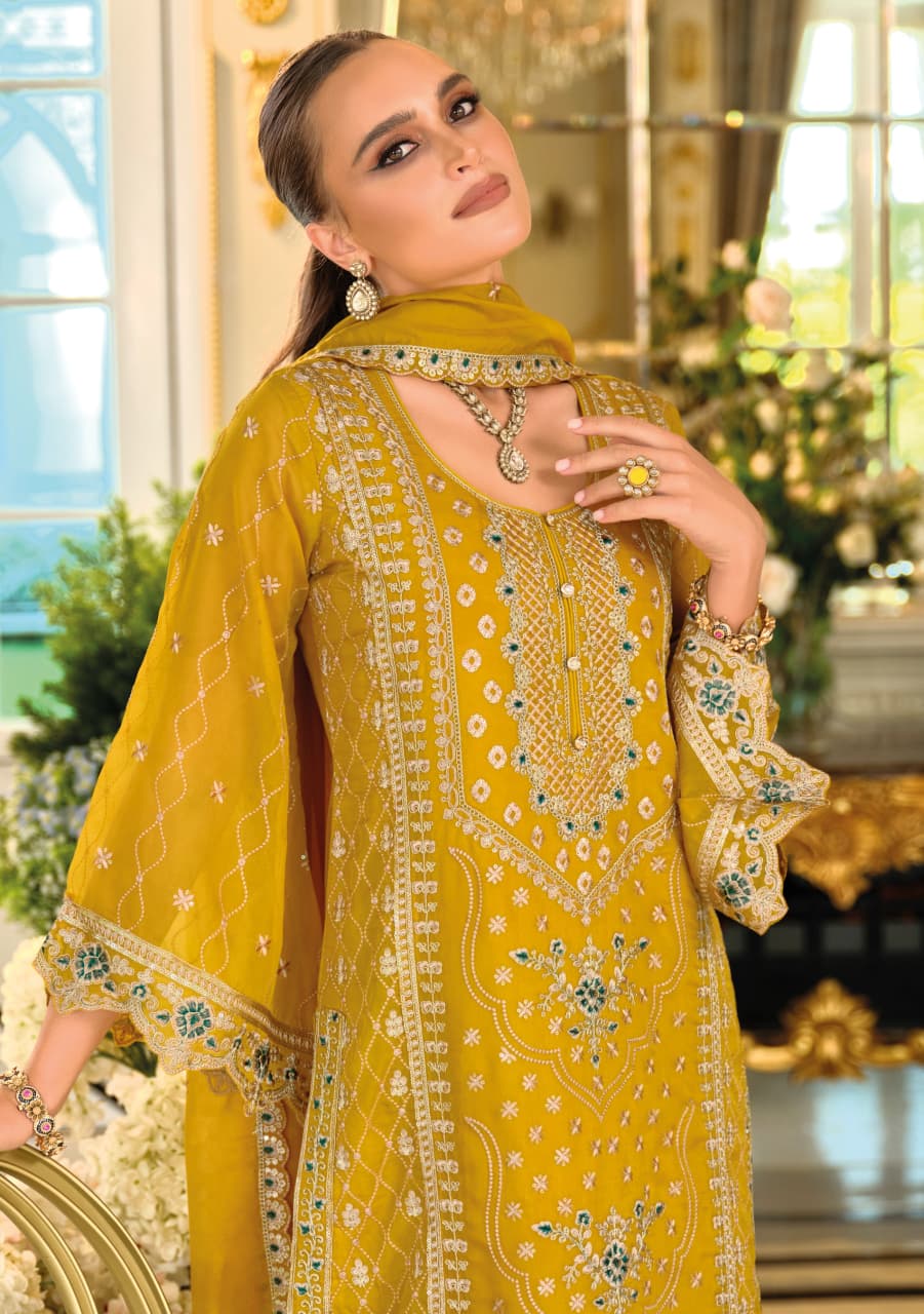 Woman in a yellow embroidered outfit with intricate patterns in an elegant indoor setting.