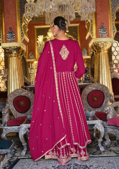 Woman in a pink traditional outfit with gold embroidery in an ornate room.