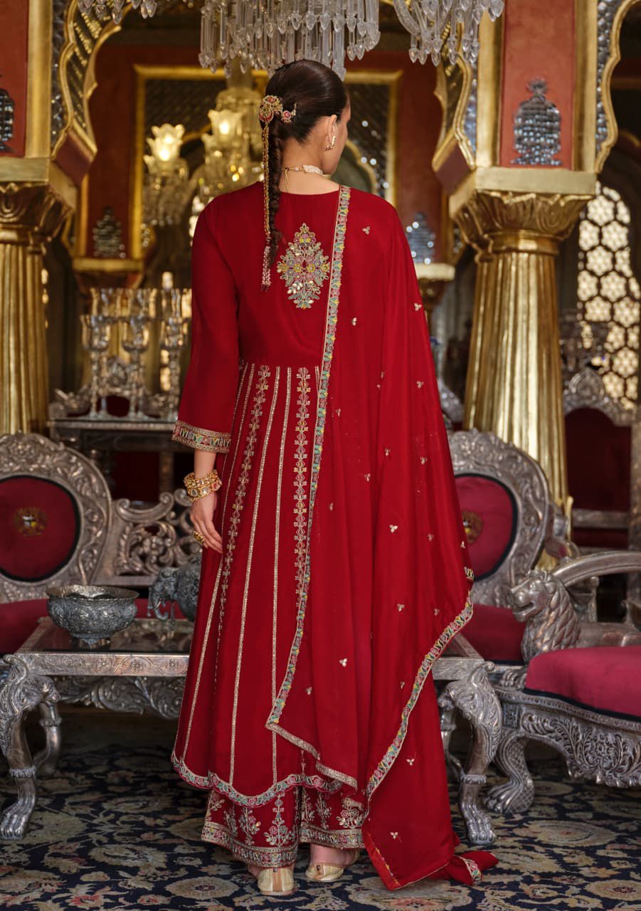 Woman in a red embroidered traditional outfit in an ornate room with chandeliers.